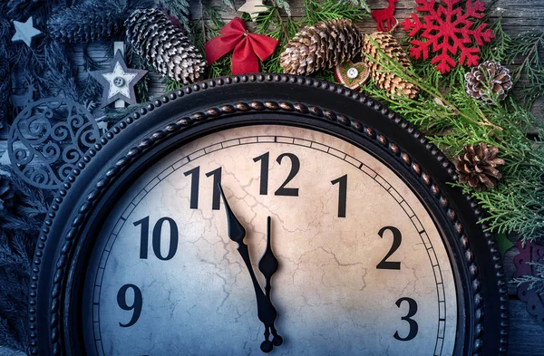 Настенные часы в рождественских или новогодних украшениях завернуты еловыми ветками и рождественскими украшениями. На часах за пять минут до полуночи . — стоковое фото