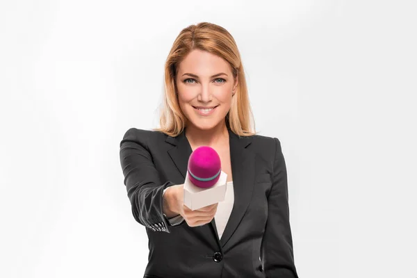 Atractivo presentador de televisión rubia sosteniendo un micrófono y apunta a un objeto . — Foto de Stock