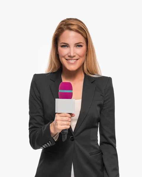 Attractive blonde TV presenter holding a microphone and points to an object. — Stock Photo, Image