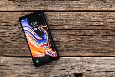 Samsung Galaxy Not 9 smartphone geliştirdi ve Samsung Electronics tarafından pazarlanan bir ahşap zemin üzerine.