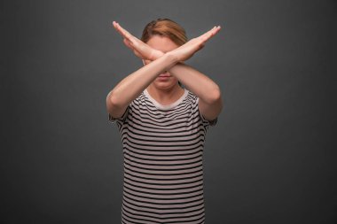 Güzel kadın tutuşup geçmeye çapraz. Protesto veya yasak. Gri arka plan üzerinde.
