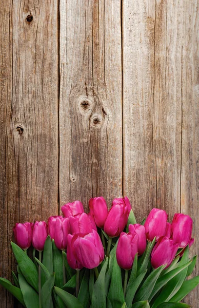 A bouquet of pink tulips on a wooden plank table. — Stock Photo, Image