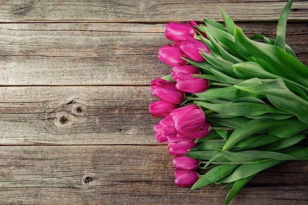 Un ramo de tulipanes rosados sobre una mesa de madera. — Foto de Stock