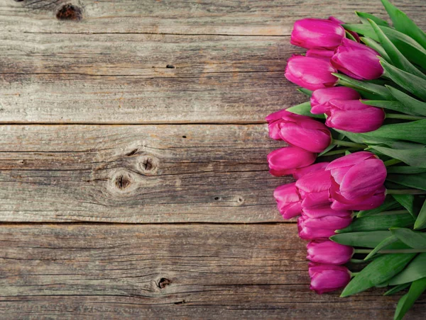 A bouquet of pink tulips on a wooden plank table. — Stock Photo, Image