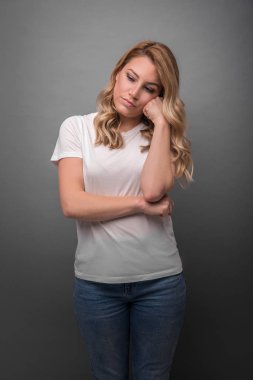 Sarışın üzgün ve gri arka plan üzerinde dalgın.