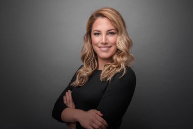 Gri bir arka planda koyu kıyafetler çekici sarışın.