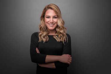 Gri bir arka planda koyu kıyafetler çekici sarışın.