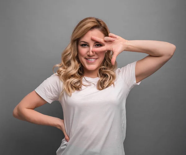 stock image Funny blondie on gray background shows a gesture of dance.