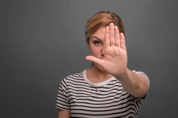 A woman pulls her hand palm forward. Stop sign. On a gray background. — Stock Photo, Image