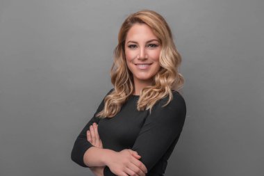 Gri bir arka planda koyu kıyafetler çekici sarışın.