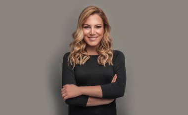 Gri bir arka planda koyu kıyafetler çekici sarışın.