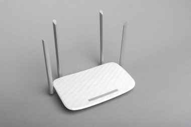 Gri arka planda dört antenli beyaz modern Wi-Fi yönlendirici.