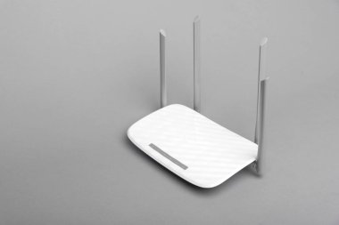 Gri arka planda dört antenli beyaz modern Wi-Fi yönlendirici.