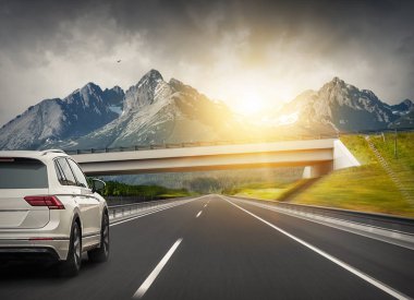 Araba bir dağ sırasının arka planında karayolu üzerinde hızlı sürücüler.