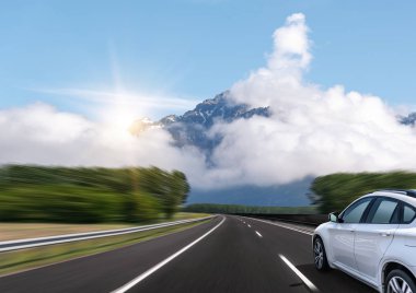 Araba bir dağ sırasının arka planında karayolu üzerinde hızlı sürücüler.