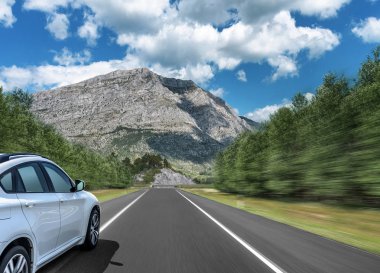 Araba bir dağ sırasının arka planında karayolu üzerinde hızlı sürücüler.