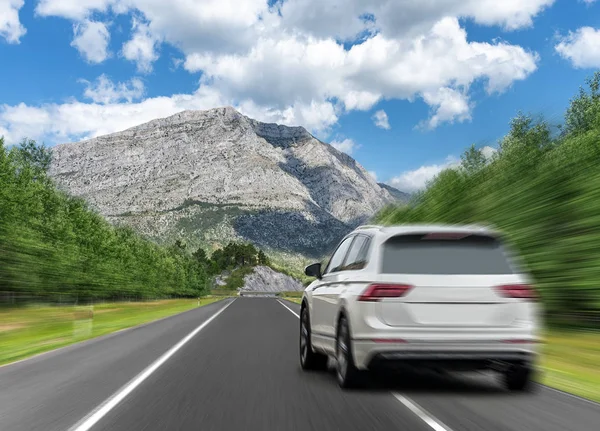 자동차는 산맥을 배경으로 고속도로에서 빠르게 운전합니다.. — 스톡 사진
