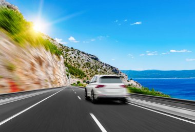 Beyaz araba denize yol boyunca koşar.