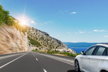 Beyaz araba denize yol boyunca koşar.