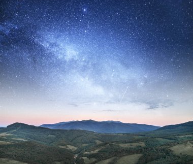 Bir dağ manzarasına karşı yıldızlı gökyüzü.