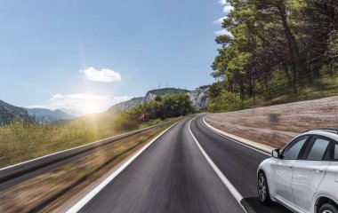 Araba, dağlar ve ormanlar arasında yolda ilerliyor..