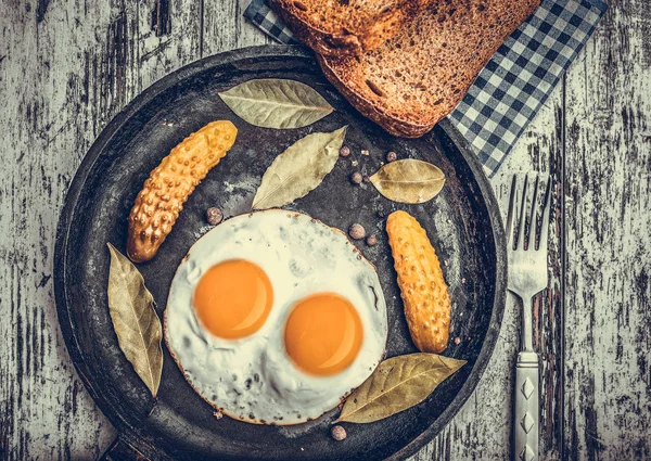 Spiegeleier in einer Pfanne. Roggen-Toast und eingelegte Gurken neben Spiegeleiern. — Stockfoto