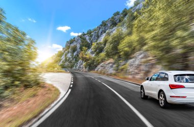 Araba, dağlar ve ormanlar arasında yolda ilerliyor..