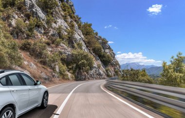 Araba, dağlar ve ormanlar arasında yolda ilerliyor..