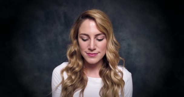 Attractive blonde speaks by a mobile phone on a dark background. — Stok Video