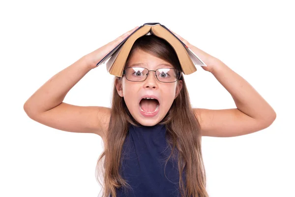 Little girl with an open book on her head is angry. — Stock Photo, Image