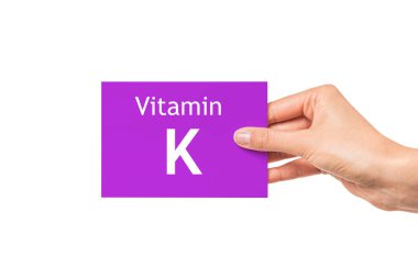 Kadın eli K vitamini yazılı bir kart gösteriyor. K vitamini..