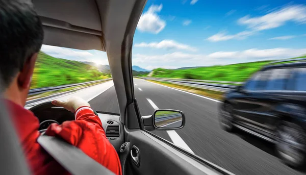 Un homme conduit une voiture sur une autoroute de banlieue. — Photo