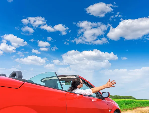 Frau im roten Auto vor dem Hintergrund eines Feldes außerhalb der Stadt. — Stockfoto