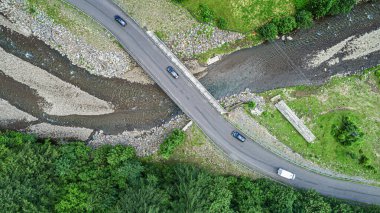 Dağlardaki ormanın arka planında nehrin üzerindeki otomobil köprüsü..