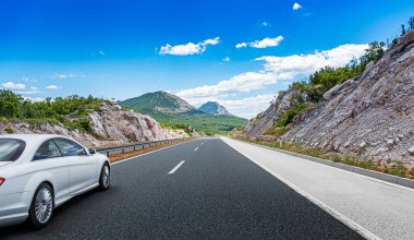 Beyaz araba, güzel bir kırsal alanın arka planına doğru hızla ilerliyor..