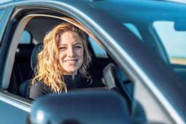 Arabadaki sarışındı. Çekici bir kadın araba kullanıyor..