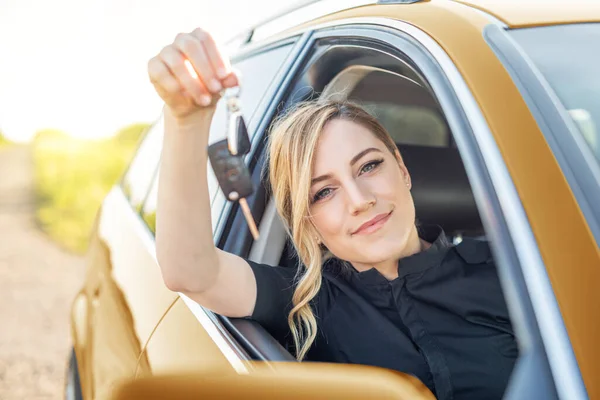 Car purchase or rental. The woman driver shows the key to the car.