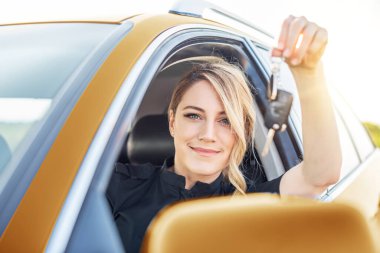 Araba almak ya da kiralamak. Kadın sürücü arabanın anahtarını gösteriyor..