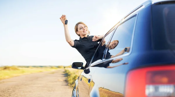 Car purchase or rental. The woman driver shows the key to the car.