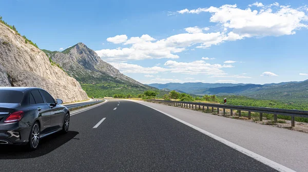 Černé auto se řítí po silnici na pozadí krásné krajiny. — Stock fotografie