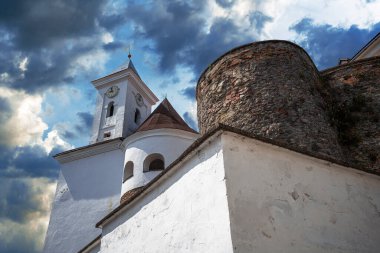 Kadim taş kale kulesi ve onun güçlendirilmiş duvarları renkli günbatımı bulutlarıyla dolu canlı bir gökyüzüne karşı..