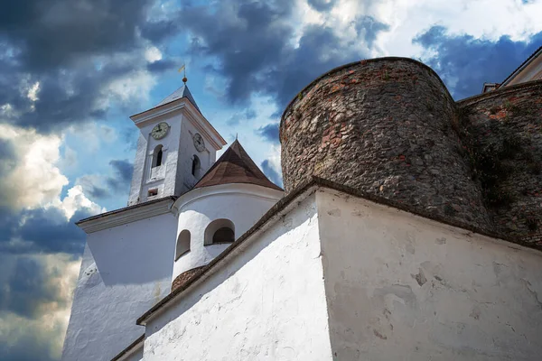 Kadim taş kale kulesi ve onun güçlendirilmiş duvarları renkli günbatımı bulutlarıyla dolu canlı bir gökyüzüne karşı..