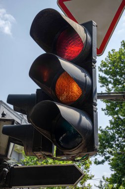 Şehir kavşağında kırmızı ve sarı ışıkların yandığını gösteren bir trafik ışığı, şehir trafik kontrolü ve yol güvenliğini simgeliyor..