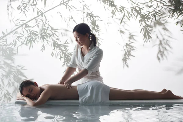 亚洲年轻妇女在水疗沙龙接受身体按摩的侧视图 — 图库照片