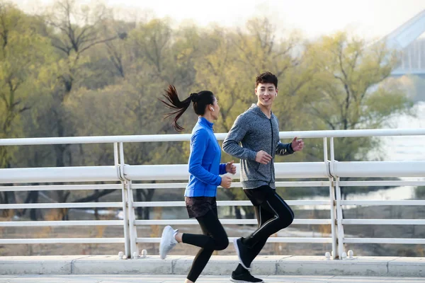 Oldalnézetből Sportos Fiatal Ázsiai Pár Mosolyogva Egymást Kocogás Együtt Hídon — Stock Fotó