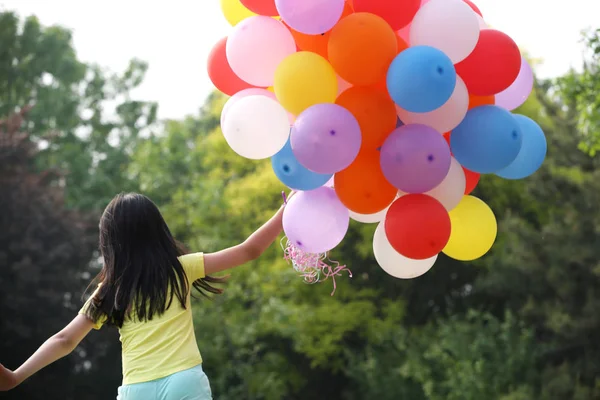 Mädchen hält Bündel Luftballons in der Hand — Stockfoto