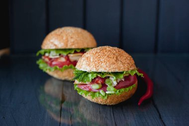 chili biber ile karanlık bir arka plan üzerinde iki iştah açıcı Burger