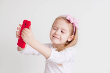 küçük kız selfie kırmızı bir akıllı telefon ile yapar