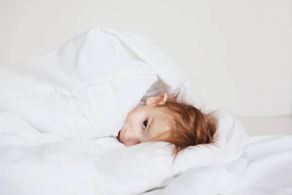 little girl sleeping under a white blanket