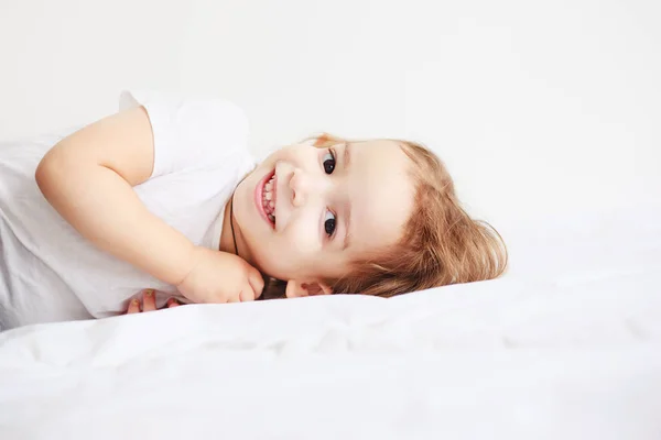 Niña Sonriendo Acostada Una Cama Imagen de stock